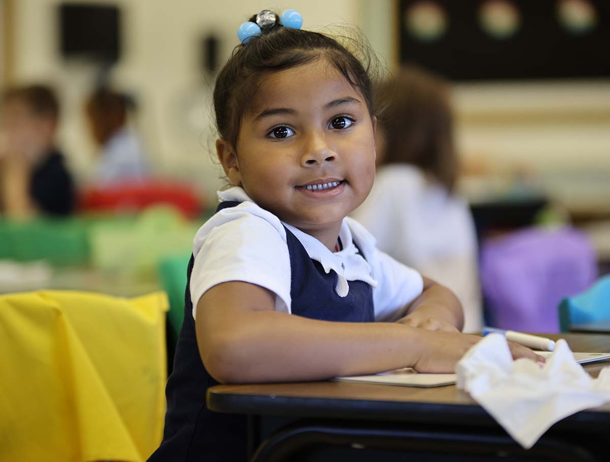 Elementary student smiling and posing together in a classroom.